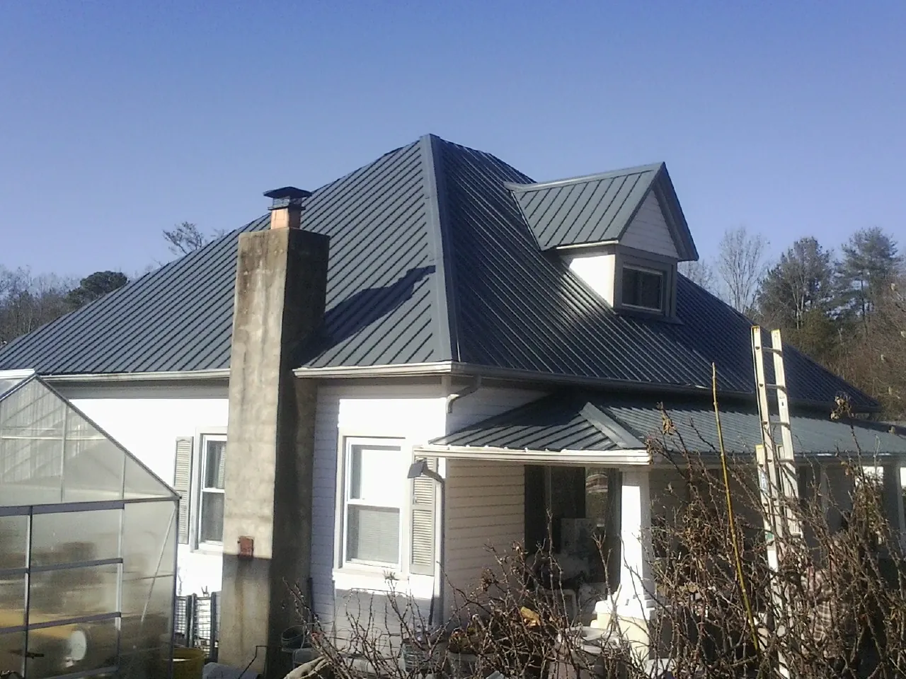 Dark blue standing seam metal roof on a white farmhouse with dormer — Slate & Tile Roof Repair by Roofing Brothers in Newbury Park