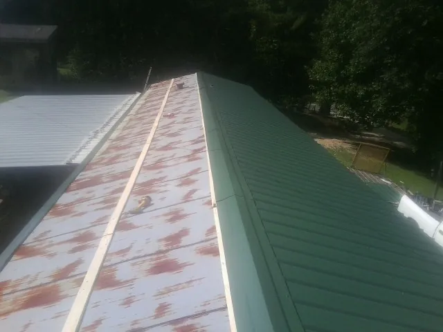 Old rusted panels beside newly installed green metal roofing — Wind Damage Roof Repair by Roofing Brothers in Newbury Park