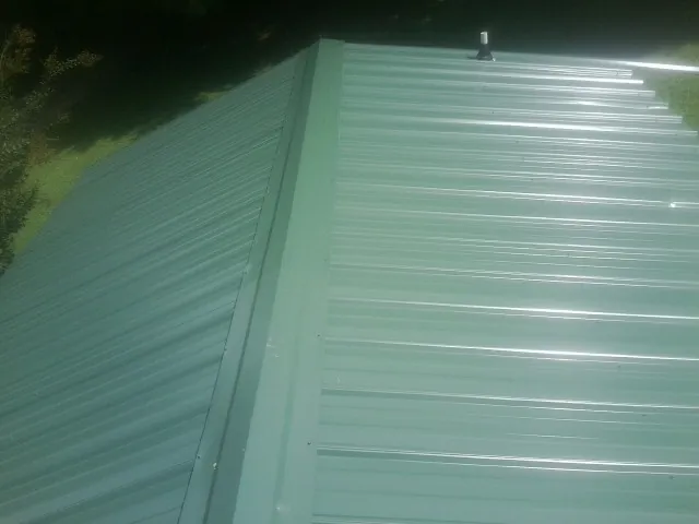 New green metal panels meeting at the ridge of a roof — Flat Roof Repair work by our crew in Newbury Park