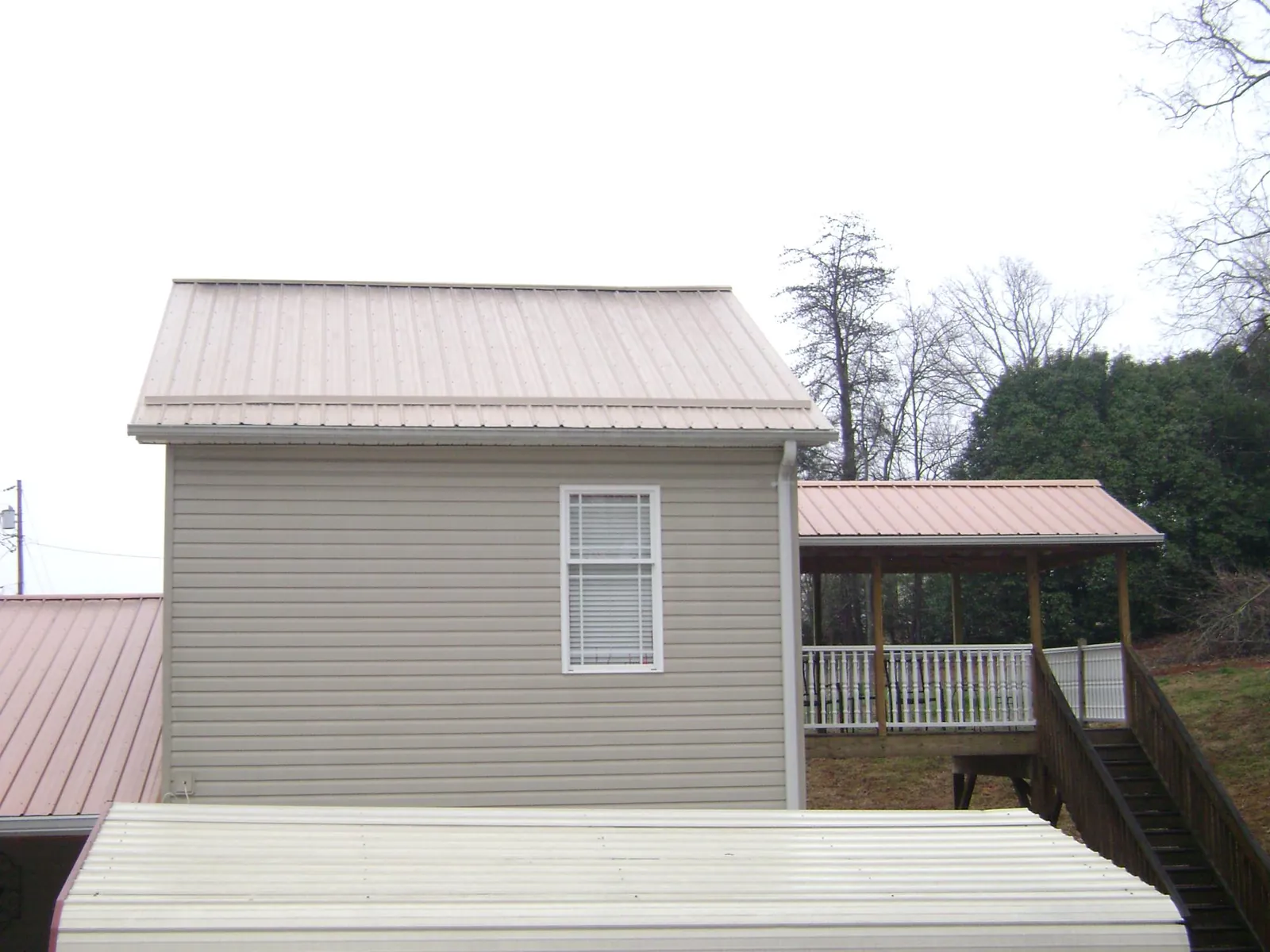 Tan metal roofs on a two story addition and attached porch, from a Roof Replacement job in Newbury Park
