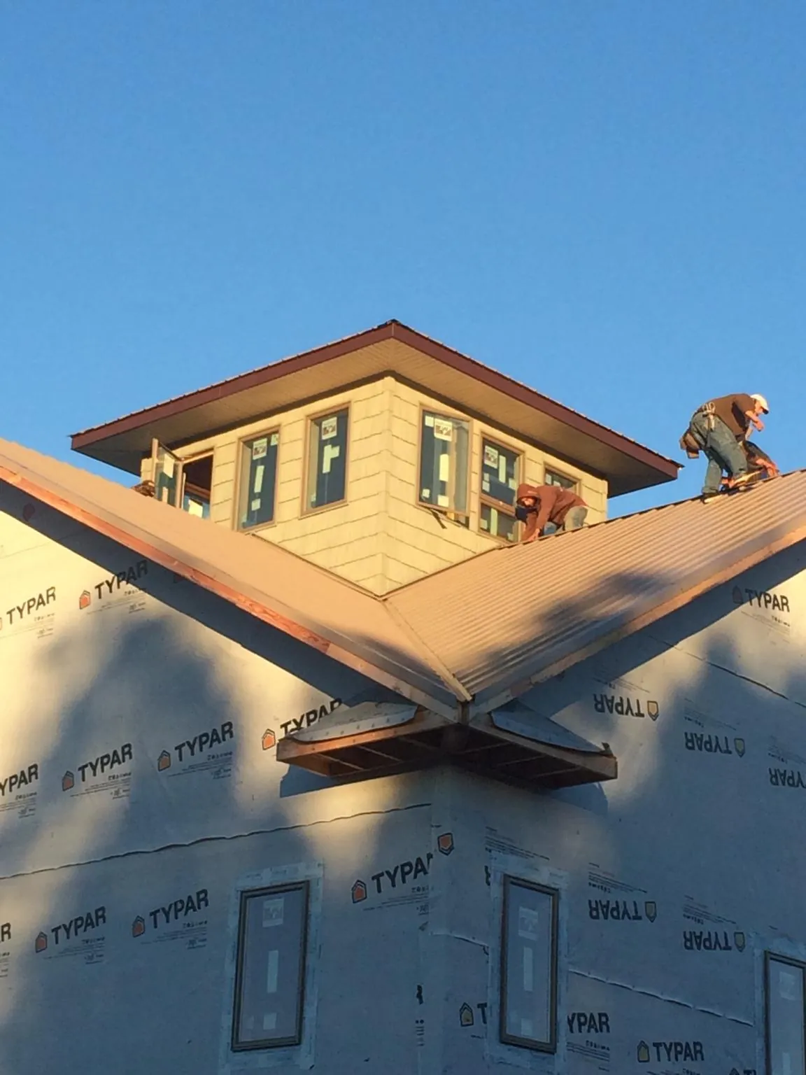 Roofers working around a rooftop cupola on a new metal roof at sunset — Roof Waterproofing in Newbury Park by Roofing Brothers